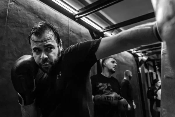 Un cadre parisien frappant un sac de boxe anglaise dans un club moderne.
