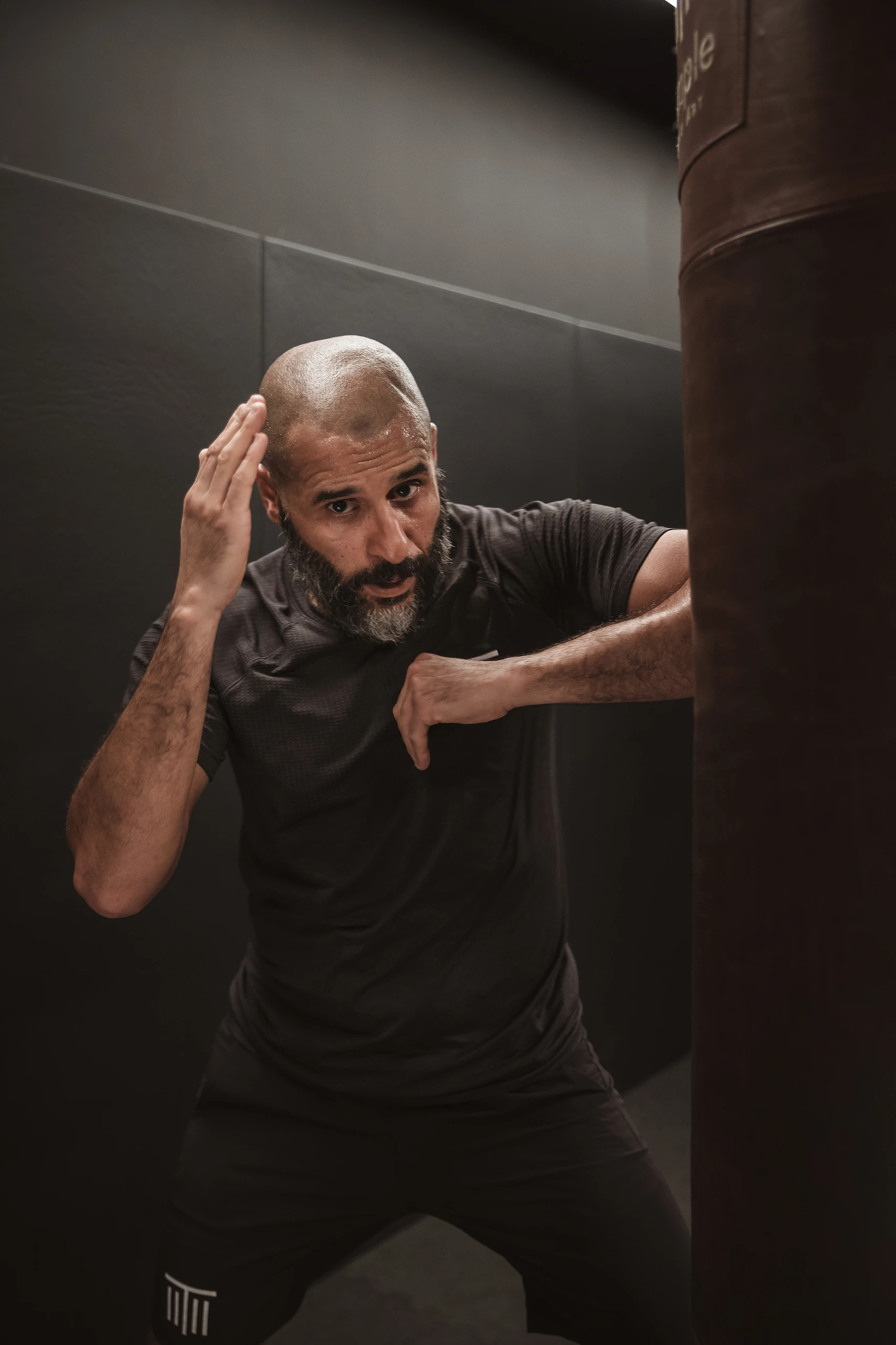Coach de boxe thaïlandaise s'entraînant sur sac dans un club de boxe à Paris